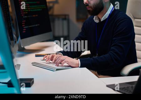 Immagine ritagliata di uno sviluppatore di software barbato che scrive codice e digita sulla tastiera del computer nello spazio di copia dell'ufficio Foto Stock