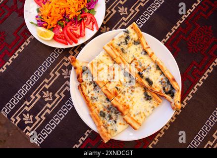 Focaccia turca vegetariana con insalata su un panno di tovaglia a motivi turchi Foto Stock