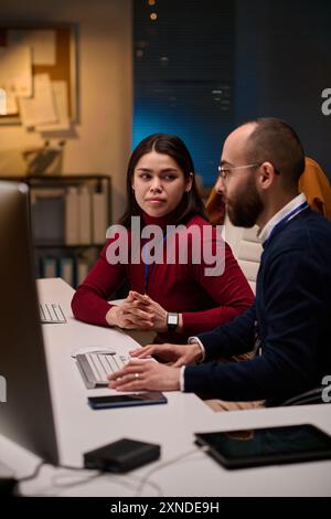 Ritratto verticale del team di sviluppo software che collabora in ufficio con una giovane donna che guarda a una collega Foto Stock