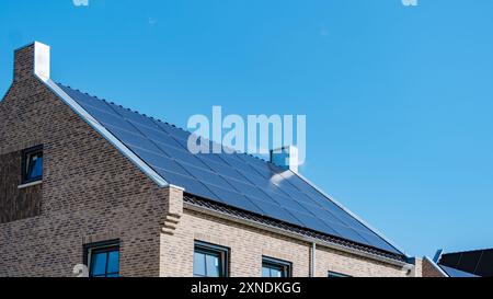 Un'elegante casa è dotata di pannelli solari sul tetto, che sfruttano la luce solare per l'energia in un cielo azzurro. Zonnepanelen, Zonne energie, traduzione: Pannello solare, Sun Energy Foto Stock