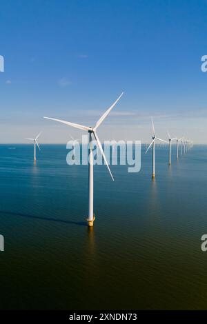 Turbine eoliche alte che sfruttano i venti costieri, trasformando l'energia in elettricità contro un cielo azzurro. Foto Stock