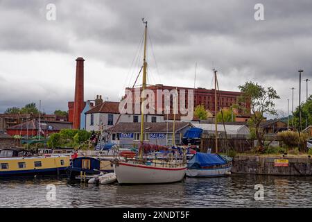 Barche ormeggiate a Underfall Yard, Bristol Harbour durante il festival del 2024, con un vecchio magazzino vittoriano sullo sfondo, l'Inghilterra. Foto Stock