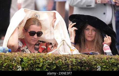 Gli appassionati di corse cercano di proteggersi dalla pioggia durante il Galway Races Summer Festival all'ippodromo di Galway. Data foto: Mercoledì 31 luglio 2024. Foto Stock