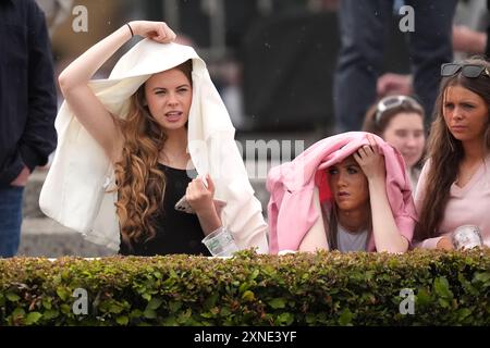 Gli appassionati di corse cercano di proteggersi dalla pioggia durante il Galway Races Summer Festival all'ippodromo di Galway. Data foto: Mercoledì 31 luglio 2024. Foto Stock