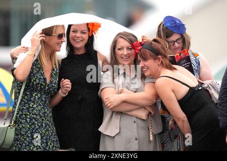 Gli appassionati di corse cercano di proteggersi dalla pioggia durante il Galway Races Summer Festival all'ippodromo di Galway. Data foto: Mercoledì 31 luglio 2024. Foto Stock