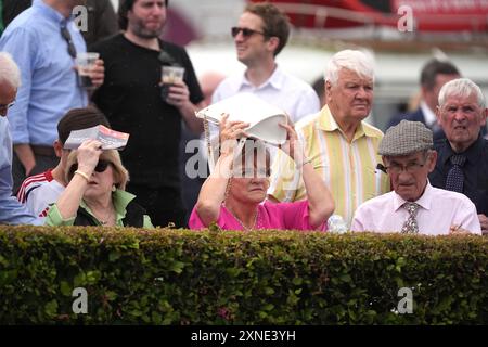 Gli appassionati di corse cercano di proteggersi dalla pioggia durante il Galway Races Summer Festival all'ippodromo di Galway. Data foto: Mercoledì 31 luglio 2024. Foto Stock