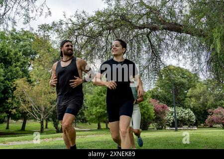 Un gruppo diversificato di persone si vede correre attraverso un vivace parco urbano verde, rimanendo in salute e in forma Foto Stock
