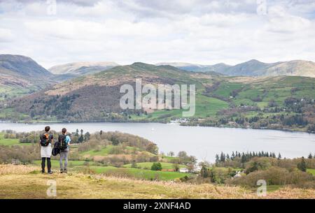 CUMBRIA, Regno Unito - 20 aprile 2024. Una giovane coppia si trova sulla collina di Latterbarrow in primavera e si affaccia sul lago Windermere e sul paesaggio del Lake District Foto Stock