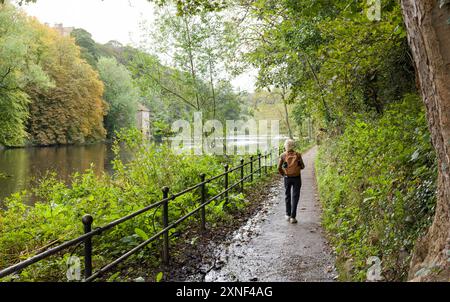 DURHAM, Regno Unito - 11 ottobre 2023. Donna che cammina da sola lungo la passeggiata lungo il fiume sulla riva del fiume indossa un abbigliamento nel centro di Durham. Durham, Inghilterra, Regno Unito Foto Stock