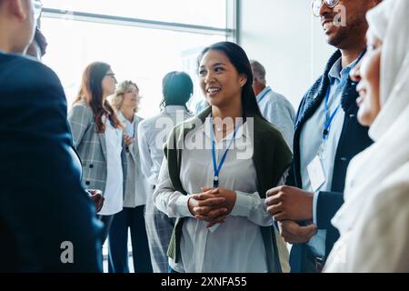 Gruppo di professionisti, uomini d'affari e donne d'affari diversi, che partecipano a un evento congressuale. Stanno sorridendo, conversando e coinvolgendo me Foto Stock