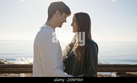 Una coppia amorevole che abbraccia il mare, evidenziando un momento di pace tra un uomo e una donna su una spiaggia. Foto Stock