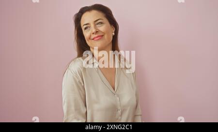 Donna ispanica di mezza età che sorride su un morbido sfondo rosa con un abbigliamento casual. Foto Stock