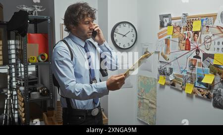 Detective ispanico in ufficio che analizza le prove a bordo mentre parla al telefono Foto Stock