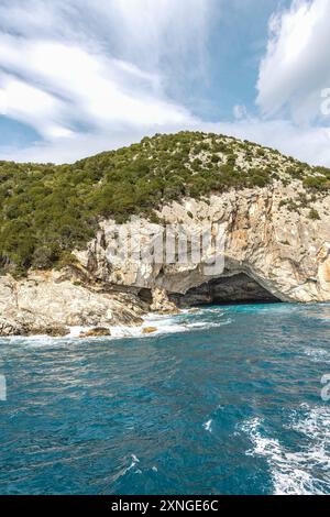 Esplora la grotta del mare di Meganisi Papanikolis nell'isola di Lefkada in Grecia, vicino a Nydri in una crociera in barca, con cielo blu e onde Foto Stock