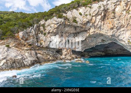 Esplora la grotta del mare di Meganisi Papanikolis nell'isola di Lefkada in Grecia, vicino a Nydri in una crociera in barca, con cielo blu e onde Foto Stock