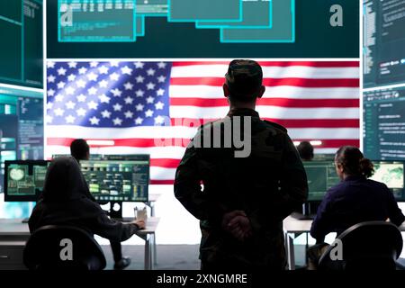 Funzionario dell'esercito AMERICANO che lavora per garantire la protezione dei server e i segreti di stato, proteggendo importanti dati di guerra ibrida nell'ufficio delle agenzie high-tech. Un soldato militare supervisiona l'attività di hacking. Foto Stock