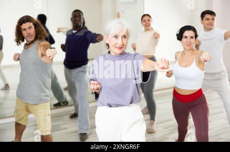 Giovane donna allegra imparando una nuova danza moderna nella lezione di danza di gruppo Foto Stock