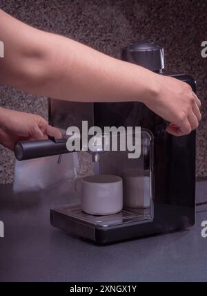 Woman Barista gestisce una macchina per preparare un caffè delizioso, primo piano di mani utilizzando la macchina per il caffè espresso. Foto Stock