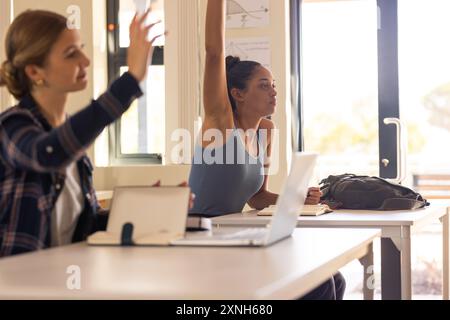 Nelle scuole superiori, gli studenti alzano la mano in classe con notebook e notebook Foto Stock