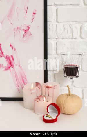 Zucca di Halloween con anello, drink e candele sul tavolo da spogliatoio in camera, primo piano Foto Stock