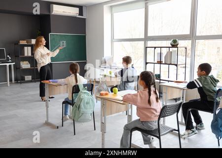 Insegnante maturo con modello molecolare che conduce lezioni di scienze ai piccoli alunni in classe Foto Stock