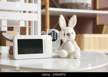 Baby monitor con coniglietto giocattolo sul tavolo nella camera dei bambini, primo piano Foto Stock