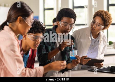 Condurre esperimenti scientifici nelle scuole superiori, studenti con insegnante che supervisiona in classe Foto Stock