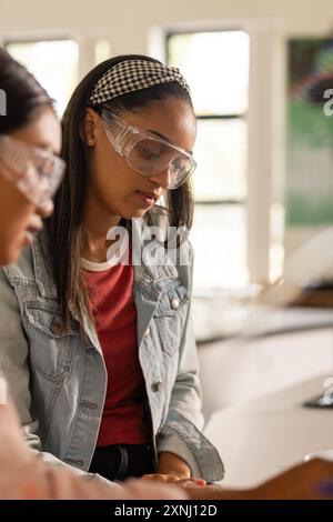 Al liceo, adolescente che indossa occhiali di sicurezza, si concentra sugli esperimenti scientifici Foto Stock