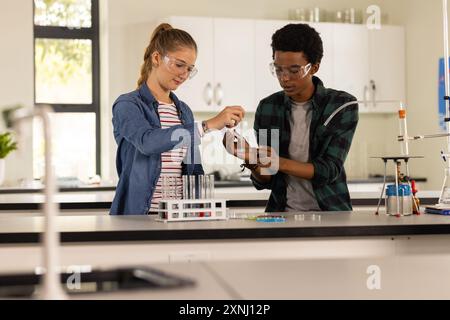 Nel laboratorio delle scuole superiori, adolescenti che conducono esperimenti scientifici con becher e provette Foto Stock