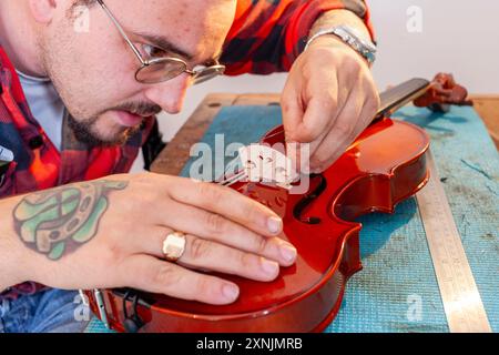 Liutaio che ripara e aggiorna violino a buon mercato Foto Stock