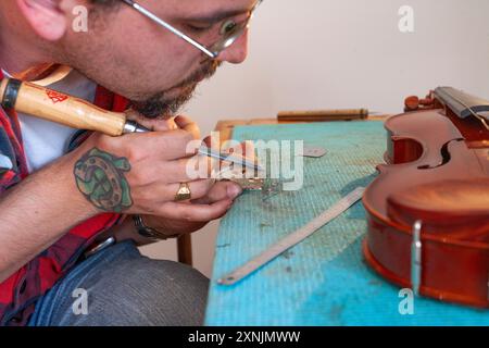 Liutaio che ripara e aggiorna violino a buon mercato Foto Stock