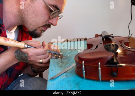 Liutaio che ripara e aggiorna violino a buon mercato Foto Stock