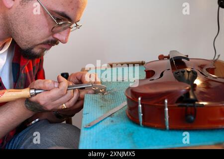 Liutaio che ripara e aggiorna violino a buon mercato Foto Stock