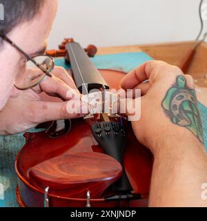 Liutaio che ripara e aggiorna violino a buon mercato Foto Stock