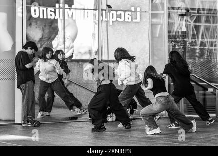 B&W Un piccolo gruppo di ragazze che cercano una danza da condividere su TikTok in Piazza Gae Aulenti, porta Garibaldi - quartiere Isola, Milano, Lombardia, Italia Foto Stock