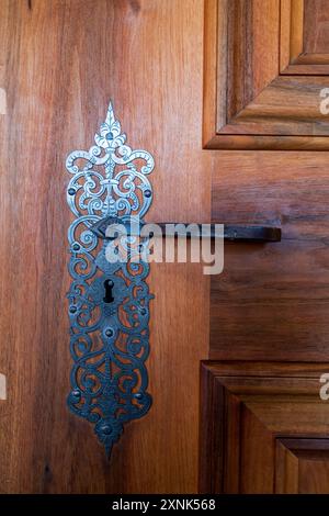 Pomello in metallo nero su porta in legno marrone. Foto Stock