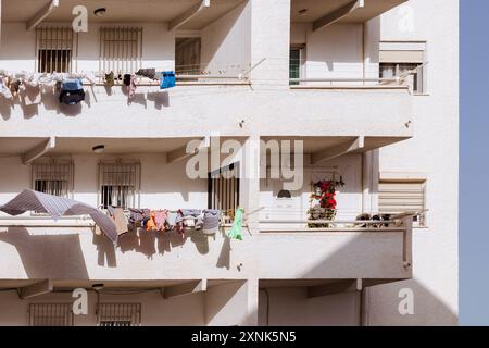 Una casa bianca di pescatori a Villajoyosa con un balcone con lavanderia sospesa e una pianta in vaso che cattura l'essenza della vita costiera del villaggio. Foto Stock