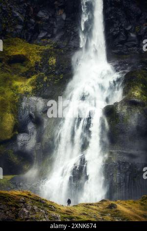 Escursionista solitario di fronte a un'enorme cascata, in Islanda, viaggiatore, turista Foto Stock