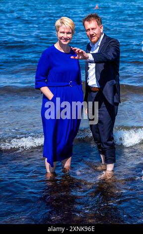 Rostock, Germania. 1 agosto 2024. Manuela Schwesig (SPD), Ministro Presidente del Meclemburgo-Pomerania occidentale, e il suo omologo sassone Michael Kretschmer (CDU) si trovano sulla spiaggia nelle acque del Mar Baltico. I due governi statali firmano un accordo per migliorare la cooperazione nel settore del turismo. Crediti: Jens Büttner/dpa/Alamy Live News Foto Stock