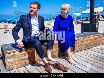 Rostock, Germania. 1 agosto 2024. Manuela Schwesig (SPD), ministro presidente del Meclemburgo-Pomerania occidentale, e il suo omologo sassone Michael Kretschmer (CDU) si sono messi le scarpe dopo una passeggiata a piedi nudi sulla spiaggia del Mar Baltico. I due governi statali firmano un accordo per migliorare la cooperazione nel settore del turismo. Crediti: Jens Büttner/dpa/Alamy Live News Foto Stock