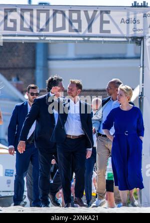 Rostock, Germania. 1 agosto 2024. Manuela Schwesig (SPD), ministro presidente del Meclemburgo-Pomerania occidentale, e il suo omologo sassone Michael Kretschmer (CDU) attraversano un cancello con la scritta "addio" sulla strada per la spiaggia del Mar Baltico. I due governi statali firmano un accordo per migliorare la cooperazione nel settore del turismo. Crediti: Jens Büttner/dpa/Alamy Live News Foto Stock