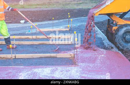 I costruttori versano e livellano calcestruzzo bagnato pronto all'uso nella cassaforma durante la costruzione di nuovi percorsi pedonali Foto Stock