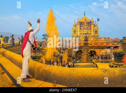 Un devoto lancia polvere di curcuma al vibrante tempio di Jejuri, Pune Maharashtra, durante una celebrazione del festival. Foto Stock