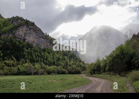 catena montuosa con una strada che la attraversa. La strada è sporca e il cielo è nuvoloso Foto Stock