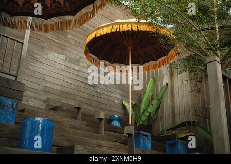 I posti a sedere in stile scala in legno massiccio raggiungono un'estetica rustica e moderna industriale, con decorazioni etniche tradizionali a ombrello Foto Stock