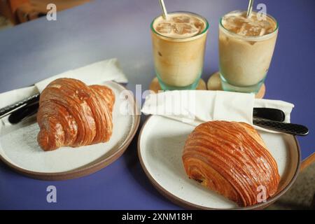 Un piatto di croissant e pain au chocolat accompagnati da caffè ghiacciato Foto Stock