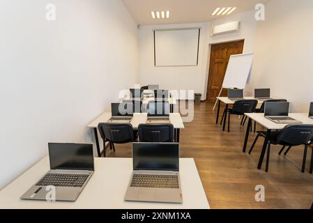 Interno di una moderna aula con scrivanie, sedie e computer portatili. Sala conferenze vuota con computer portatile sul tavolo in ufficio. Affari d'ufficio. Sala conferenze Foto Stock