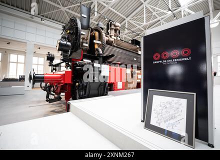 Meiningen, Germania. 1 agosto 2024. Un leggio con la dicitura "Dampflok Erlebniswelt" davanti ad una locomotiva a vapore. L'ex edificio della mensa della fabbrica di locomotive a vapore di Meiningen ospiterà la "Steam Locomotive Experience" dal 2 agosto 2024. Crediti: Hannes P. Albert/dpa/Alamy Live News Foto Stock