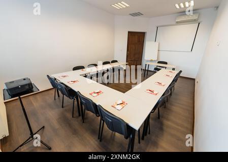 Sala conferenze vuota nel moderno ufficio. Interno di un'aula con pareti bianche e pavimento in legno. Affari d'ufficio. Sala conferenze con panchine, TAB Foto Stock