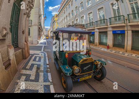 LISBONA, PORTOGALLO - 8 APRILE 2024: Trasporto turistico con divertente auto elettrica chiamata Tuk Tuk e tram d'epoca per le strade della città. Foto Stock